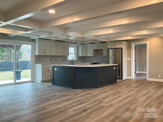 kitchen featuring a kitchen island, wood finished floors, baseboards, light countertops, and freestanding refrigerator