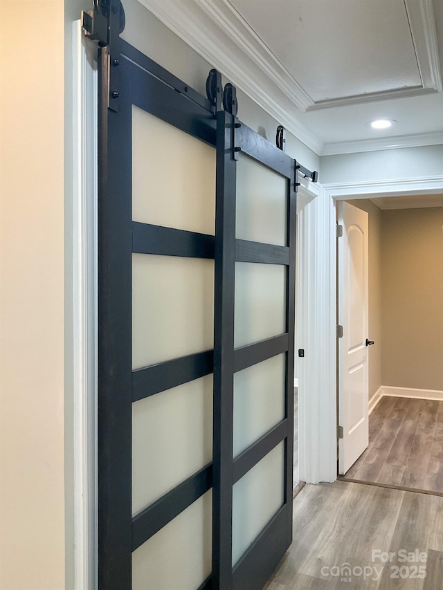 interior space with wood finished floors, crown molding, baseboards, and a barn door