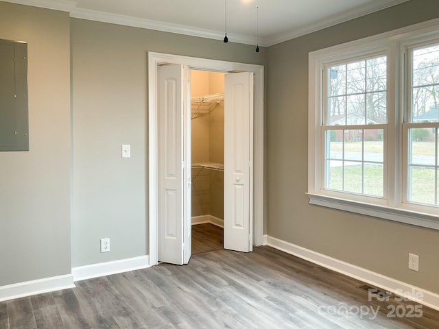 unfurnished bedroom with crown molding, electric panel, wood finished floors, and multiple windows