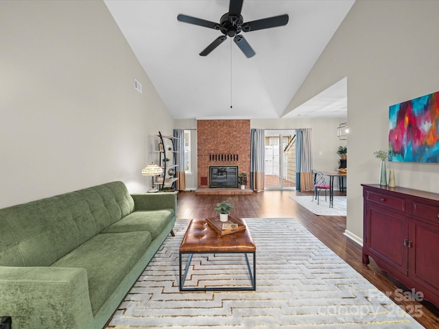 living area with dark wood finished floors, a brick fireplace, high vaulted ceiling, and ceiling fan