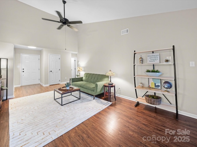 living area featuring visible vents, baseboards, high vaulted ceiling, and wood finished floors