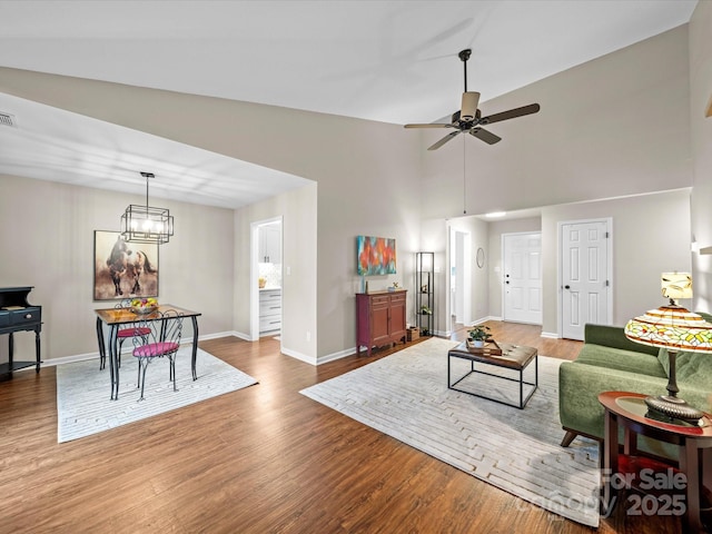 living room featuring visible vents, ceiling fan with notable chandelier, baseboards, and wood finished floors