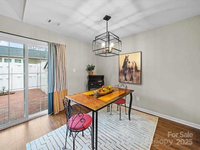 dining area featuring a notable chandelier, wood finished floors, visible vents, and baseboards