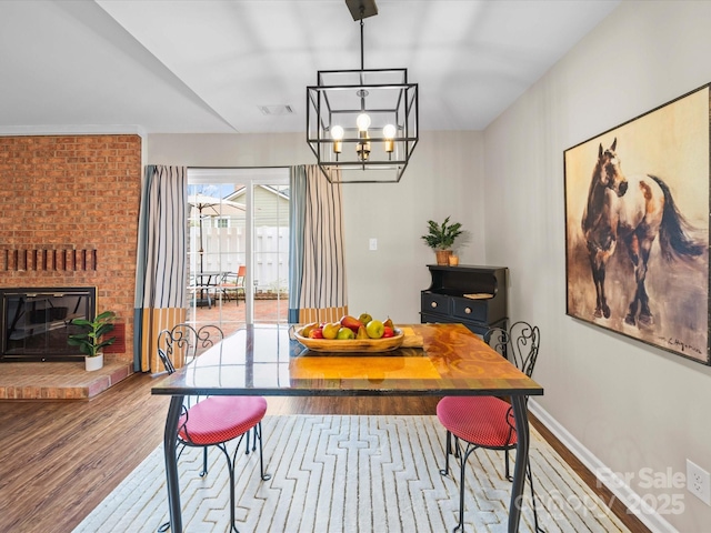 dining space with visible vents, a notable chandelier, wood finished floors, a fireplace, and baseboards