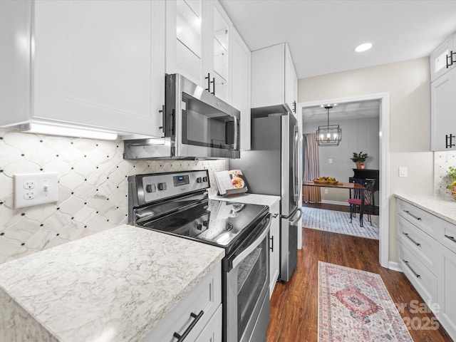 kitchen featuring dark wood finished floors, white cabinets, appliances with stainless steel finishes, tasteful backsplash, and a chandelier