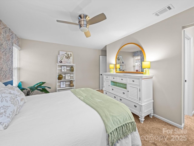 bedroom featuring visible vents, light colored carpet, a ceiling fan, and baseboards