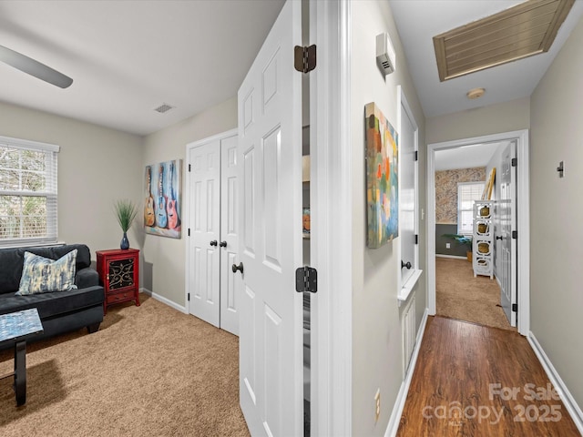 hallway with visible vents, a healthy amount of sunlight, and baseboards