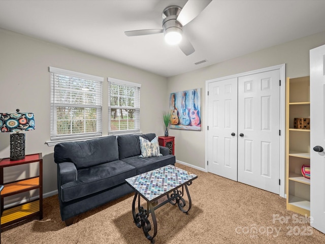 living room featuring visible vents, carpet floors, baseboards, and ceiling fan