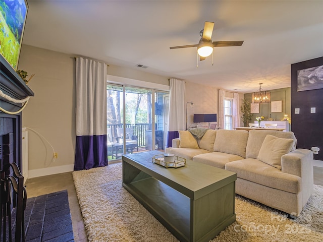 living room featuring baseboards, visible vents, and ceiling fan with notable chandelier