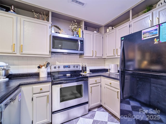 kitchen with appliances with stainless steel finishes, dark countertops, visible vents, and decorative backsplash