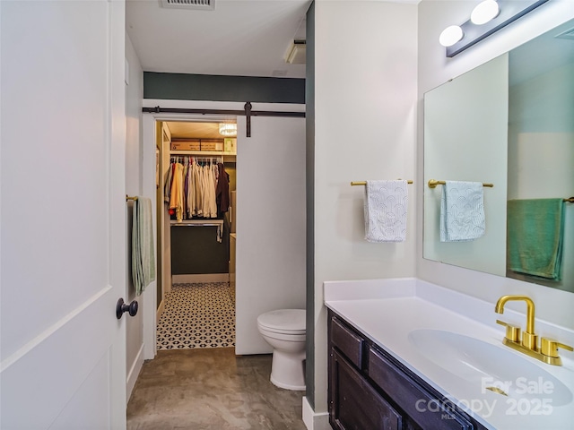 bathroom featuring toilet, visible vents, vanity, a spacious closet, and tile patterned floors