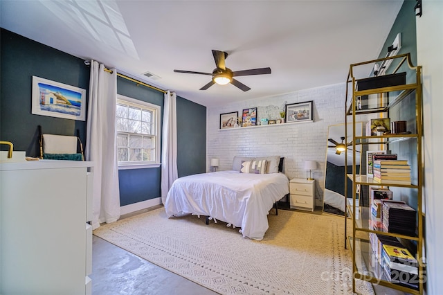 bedroom featuring concrete flooring, brick wall, an accent wall, visible vents, and baseboards