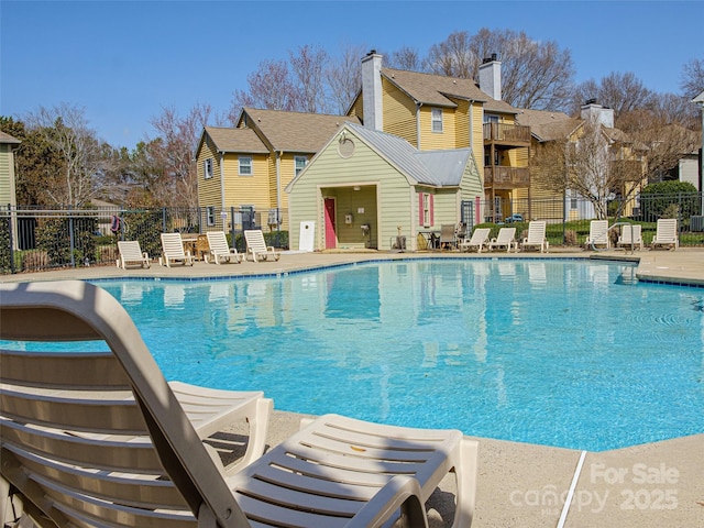 community pool with a patio area, a residential view, and fence