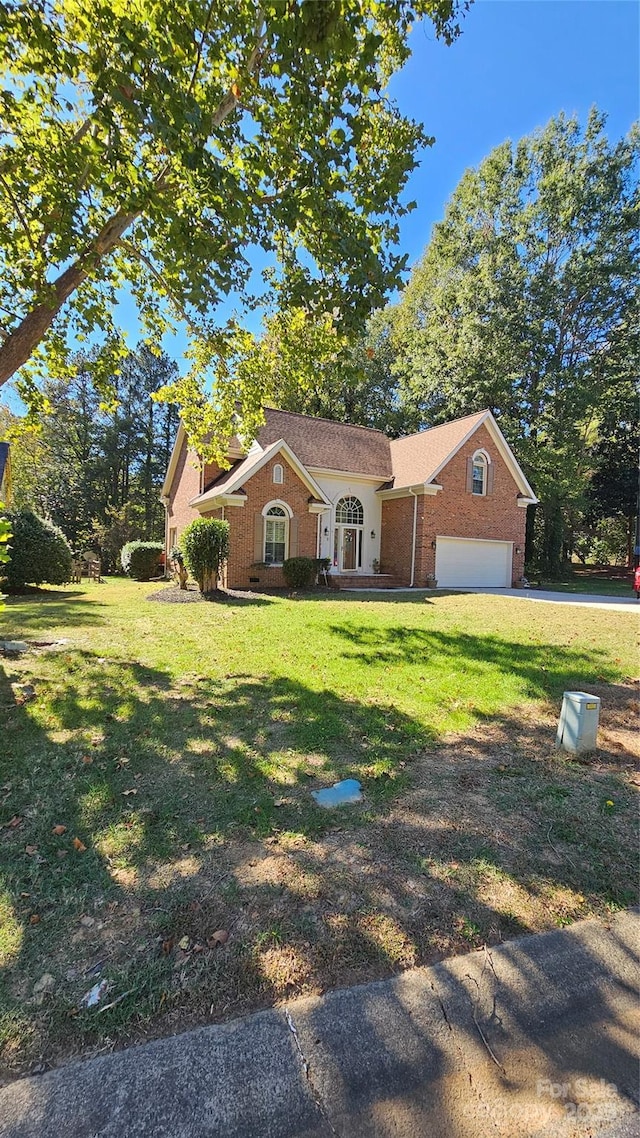 view of front of house with a garage, a front yard, and brick siding