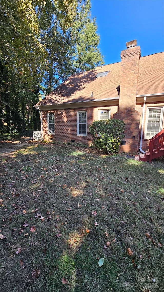 exterior space featuring crawl space, a chimney, and a front lawn