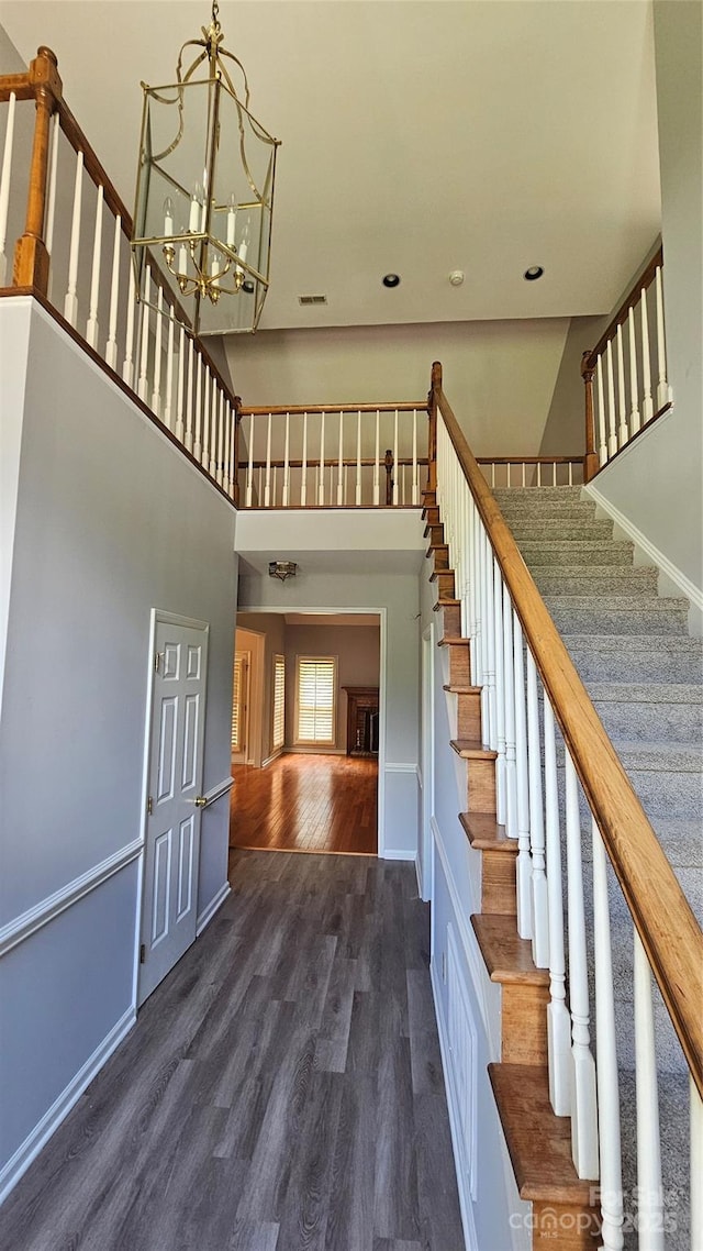 stairway featuring baseboards, wood finished floors, a high ceiling, a chandelier, and recessed lighting