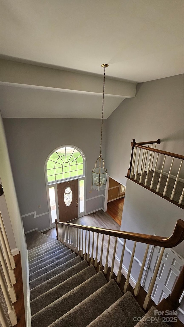 stairway featuring lofted ceiling with beams, wood finished floors, and baseboards