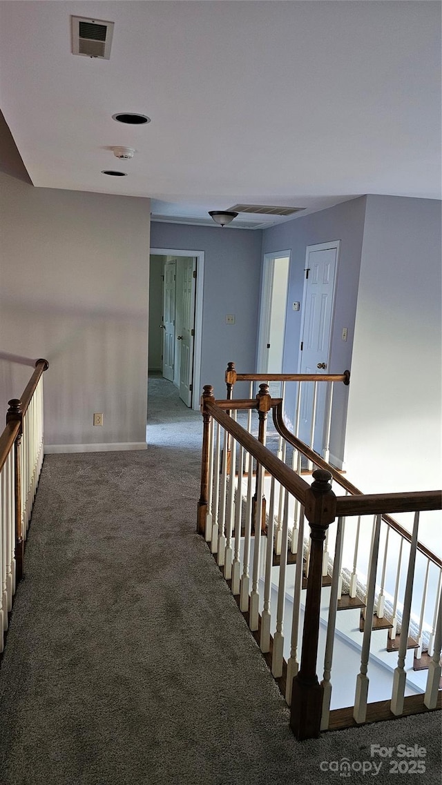 hallway with visible vents, carpet flooring, an upstairs landing, and baseboards