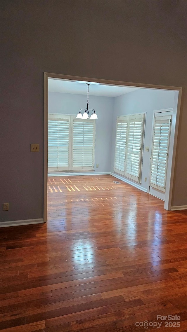 interior space with an inviting chandelier, baseboards, and wood finished floors