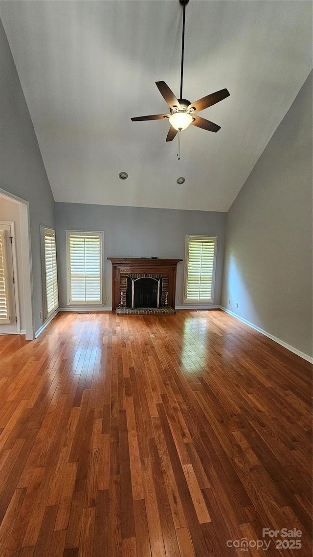 unfurnished living room with baseboards, a ceiling fan, hardwood / wood-style floors, a fireplace, and high vaulted ceiling