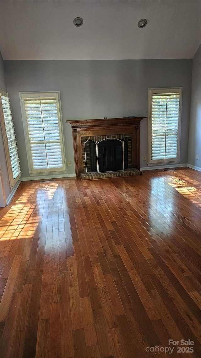 unfurnished living room with a fireplace, wood-type flooring, and a healthy amount of sunlight