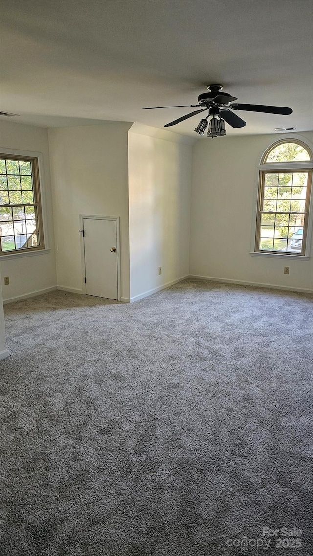 carpeted spare room featuring a ceiling fan and baseboards