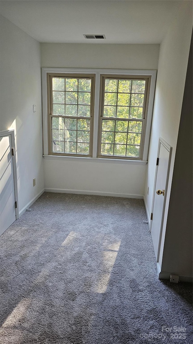 carpeted spare room with visible vents and baseboards