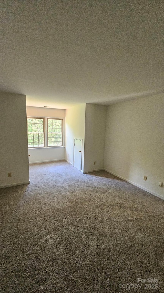 carpeted empty room with a textured ceiling and baseboards