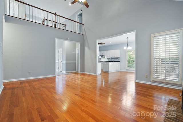 8731 Sheltonham Way, Charlotte, NC 28216 - unfurnished living room with a ceiling fan, a chandelier, a towering ceiling, and light wood-style flooring