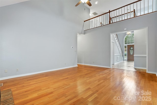 8731 Sheltonham Way, Charlotte, NC 28216 - unfurnished living room with ceiling fan, stairway, light wood-style floors, a towering ceiling, and a chandelier