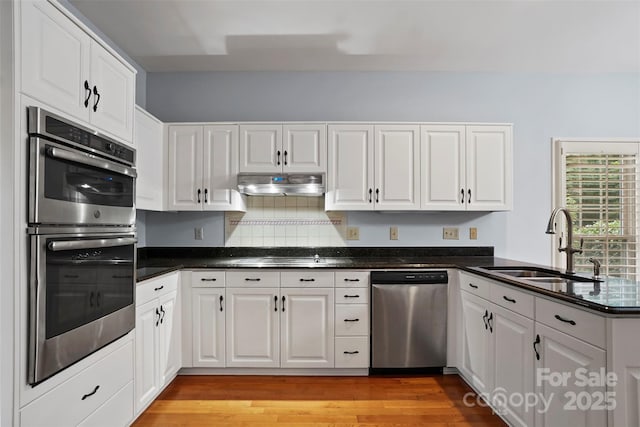 8731 Sheltonham Way, Charlotte, NC 28216 - kitchen with appliances with stainless steel finishes, white cabinetry, under cabinet range hood, a peninsula, and light wood-type flooring