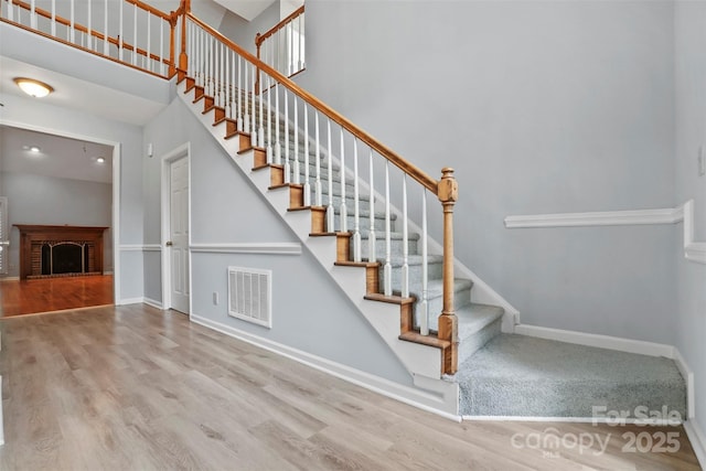 8731 Sheltonham Way, Charlotte, NC 28216 - stairs featuring wood finished floors, a towering ceiling, and a fireplace