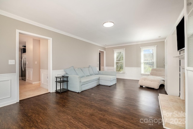 unfurnished living room featuring ornamental molding, wainscoting, and wood finished floors