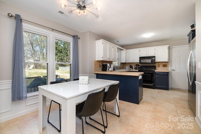 kitchen with a peninsula, white cabinets, light countertops, black appliances, and tasteful backsplash