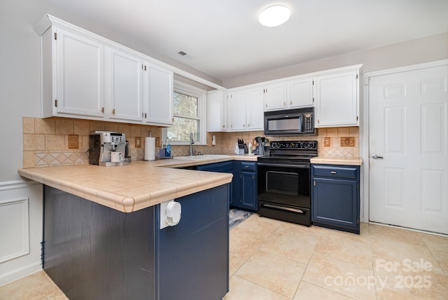 kitchen featuring blue cabinetry, white cabinetry, a sink, a peninsula, and black appliances