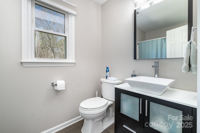 bathroom with baseboards, vanity, and toilet