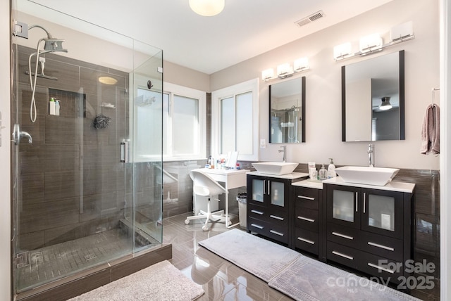 full bathroom featuring a stall shower, vanity, and visible vents