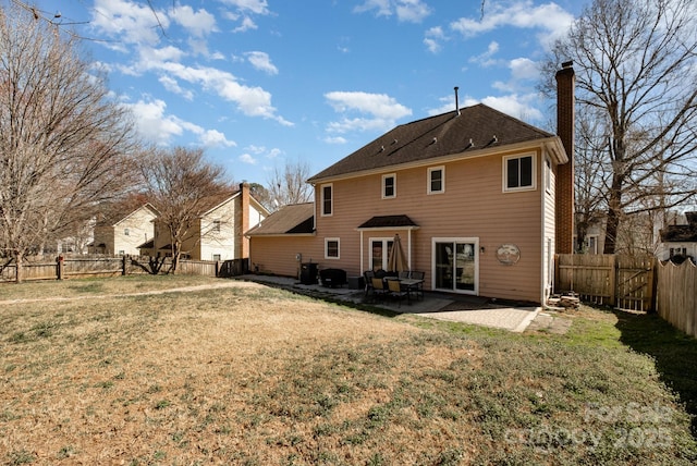 rear view of house with a yard, a chimney, a patio area, and a fenced backyard