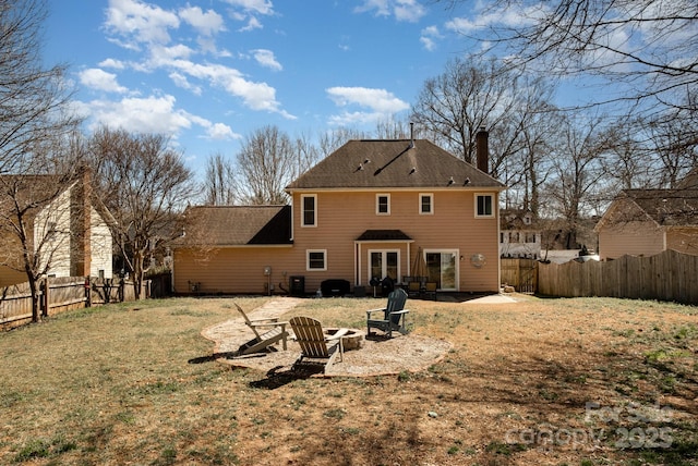 back of house featuring an outdoor fire pit, a fenced backyard, a lawn, and a chimney