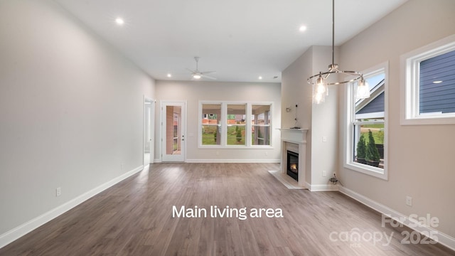 unfurnished living room featuring baseboards, a glass covered fireplace, ceiling fan, wood finished floors, and recessed lighting