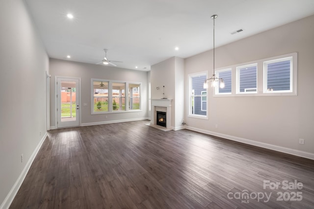 unfurnished living room featuring dark wood-type flooring, a glass covered fireplace, visible vents, and recessed lighting