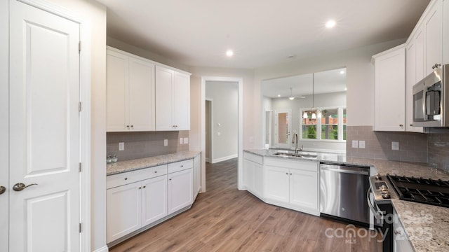 kitchen with stainless steel appliances, light wood-type flooring, white cabinetry, and a sink