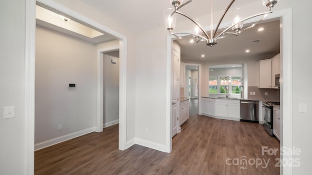 kitchen featuring appliances with stainless steel finishes, white cabinets, a sink, and wood finished floors