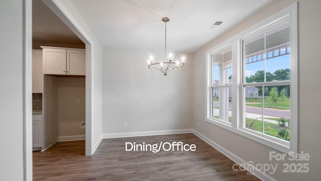 unfurnished dining area with a chandelier, visible vents, baseboards, and wood finished floors