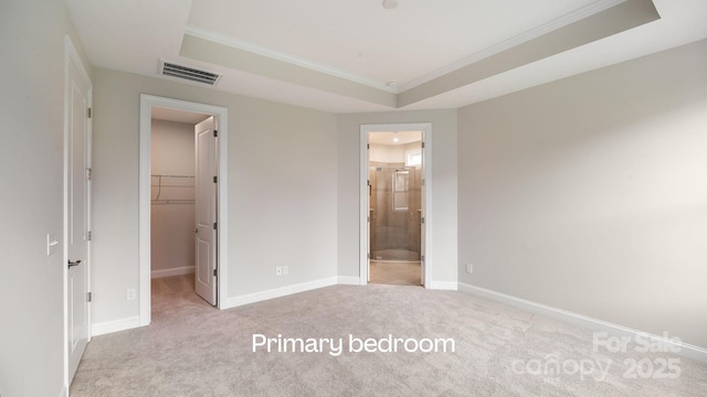 unfurnished bedroom with carpet flooring, visible vents, baseboards, a spacious closet, and a tray ceiling