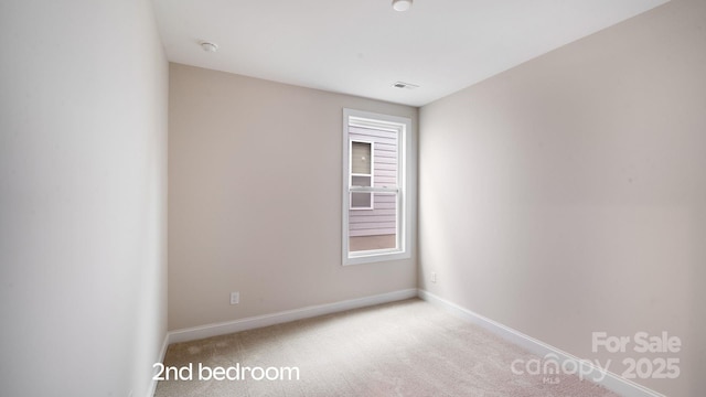 carpeted spare room with visible vents and baseboards