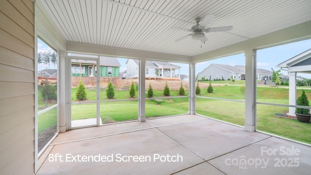 unfurnished sunroom featuring a healthy amount of sunlight, ceiling fan, and a residential view