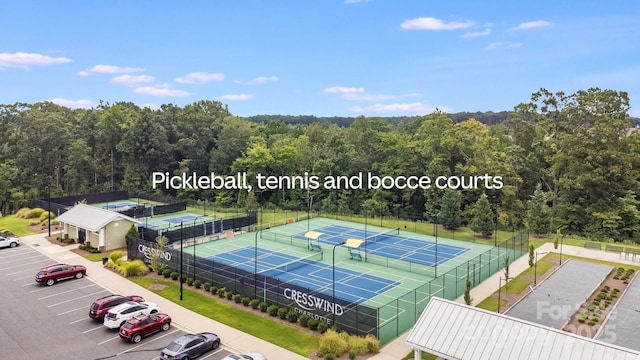 view of sport court with fence and a wooded view