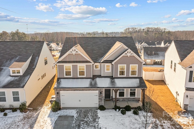 view of front of home featuring an attached garage, stone siding, fence, and board and batten siding