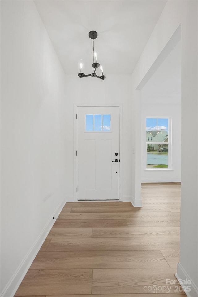 entryway featuring light wood-type flooring, baseboards, and a chandelier